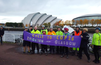 Members of the Brighton to Glasgow Bike ride pose with a banner at the end of their journey
