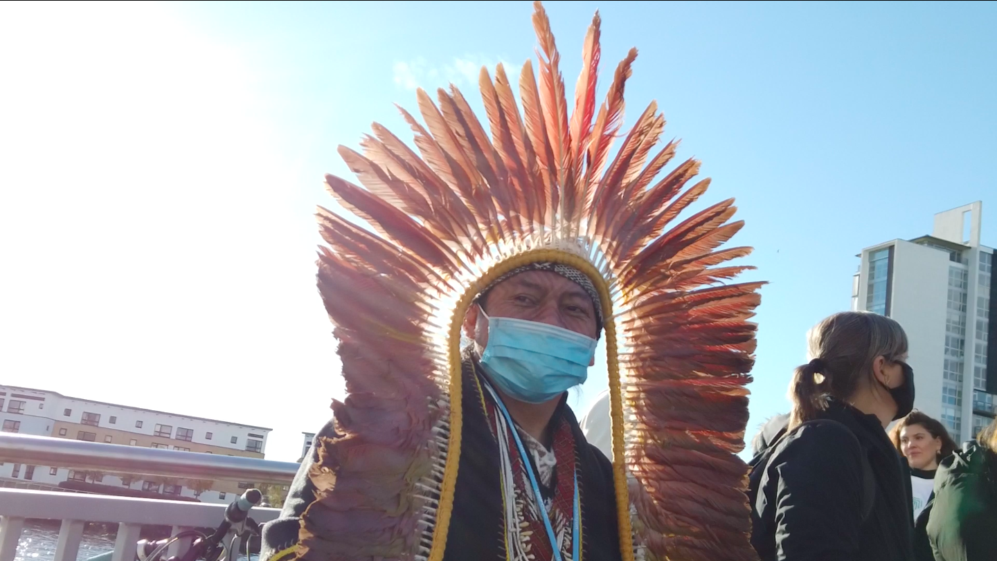 An indigenous man with a traditional head dress and surgical mask at the cop26 summit
