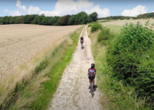 A drone still of two cyclists riding along a gravel path