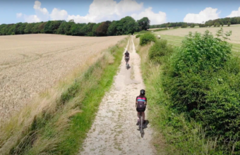 A drone still of two cyclists riding along a gravel path